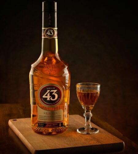 Licor 43 bottle with glass on a wooden tray, ideal for beverage promotions and still life art.